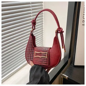 Close-up of wine red hobo bag with crocodile texture, lychee grain, and gold buckle