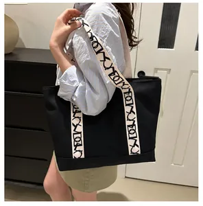 Détail d'un sac cabas en toile noire avec large bandoulière contrastée chic