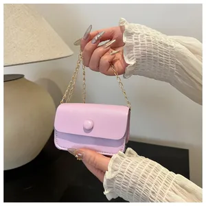 Detail view of pink mini chain bag held by hand to show its micro size and PU leather texture