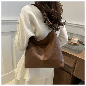 Detail of a large brown hobo bag with patchwork texture and wooden bead strap accents
