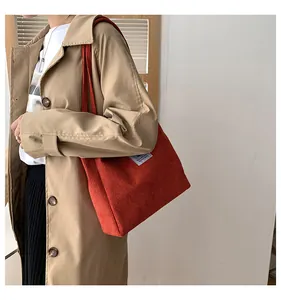 Detailed texture of orange corduroy tote bag showing ribbed fabric and fabric label