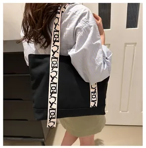 Sac fourre-tout en toile noire avec bandoulière géométrique porté pour le quotidien