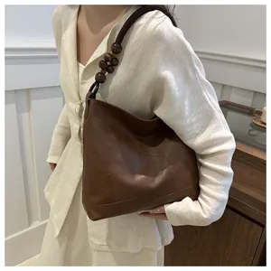 Detail view of deep brown leather tote bag featuring unique wooden bead shoulder strap
