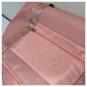 Close-up of pink water-resistant nylon travel bag fabric with visible water droplets