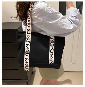 Détail du sac cabas en toile noire avec large bandoulière tissée et grand format