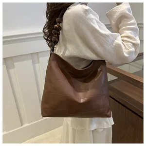 Detail of brown leather tote bag with geometric patchwork and decorative wooden beads