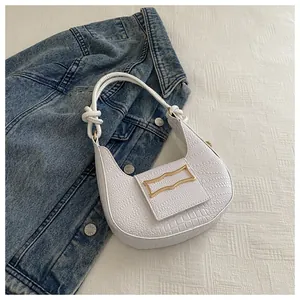 Detail of white crocodile texture underarm bag with gold geometric buckle and knotted strap
