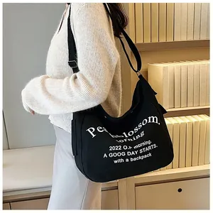 Détail du sac cabas en toile noire avec typographie blanche et bandoulière réglable
