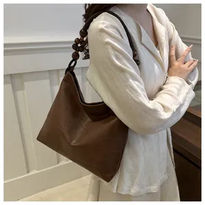 Detail of brown leather tote bag with unique dark wooden bead shoulder strap design