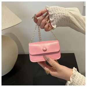 Close-up of pink mini leather shoulder bag with gold chain and round button detail