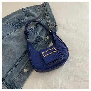 Detail of blue crocodile pattern shoulder bag featuring a gold buckle and knot handle