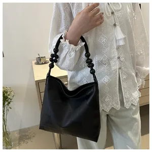 Detail of black PU leather hobo tote bag featuring unique beaded handle and geometric texture
