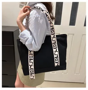 Détail du sac cabas en toile noire montrant des sangles à motifs géométriques et sa capacité