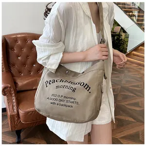 Détail du sac cabas en toile beige avec boucle magnétique et lettrage imprimé