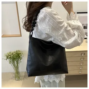 Detail of black leather tote bag with unique beaded handle and geometric patchwork