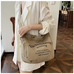 Détail du sac fourre-tout en toile kaki avec texte vintage et large bandoulière robuste