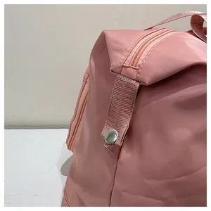Close-up of pink travel bag showing durable nylon fabric, metal snap button, and smooth zipper