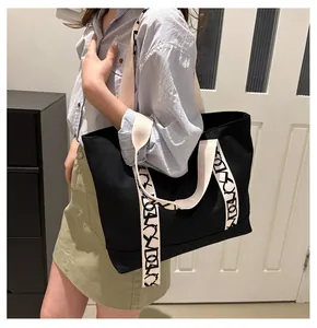 Détail d'un grand sac cabas en toile noire avec une large bandoulière à motifs crème