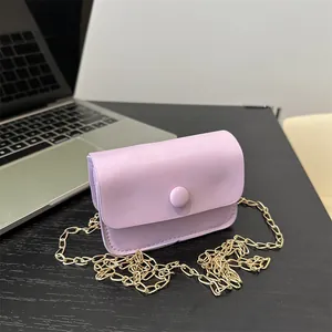 Lavender mini crossbody bag with gold chain strap on office desk with laptop