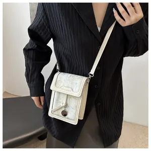 Close-up of cream crossbody phone bag with gold butterfly pattern worn by a model