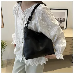 Detail of black tote bag featuring geometric patchwork leather and beaded shoulder strap