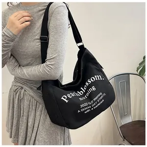 Détail de la bandoulière et des lettres blanches sur le grand sac cabas noir en toile