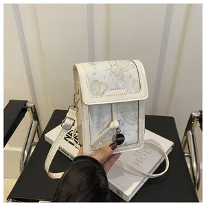 Detail of cream crossbody phone bag featuring gold butterfly embroidery and fashion logo