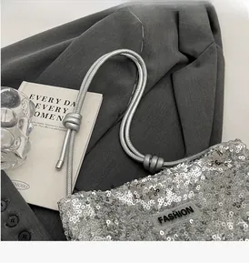 Detail of silver sequin tote bag with braided handles on a grey blazer backdrop