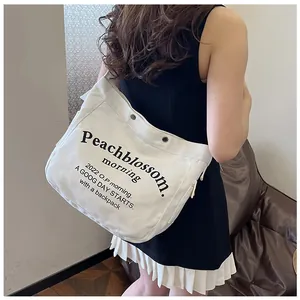 Détail du sac cabas blanc en toile avec boutons pression en métal et texte noir