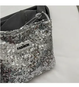 Detail of silver sequined tote bag featuring a black FASHION label and rope handles