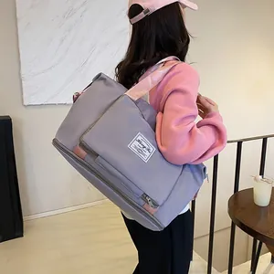 Large gray travel bag with pink straps for women shown in a cozy indoor setting