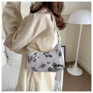 Detail of cream shoulder bag featuring black butterfly and constellation prints on leather