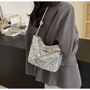 Macro detail of silver sequin tote bag with knotted shoulder strap and fashion label