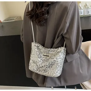 Detail of silver sequin shoulder bag with metal strap and Fashion label on brown suit
