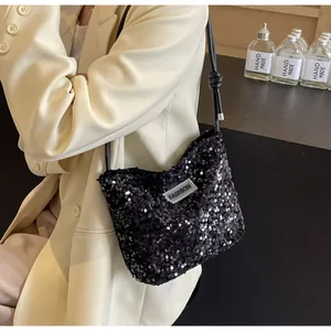 Fashionable black sequin shoulder bag with FASHION label worn on a beige blazer