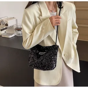 Detail of a black sequined tote bag with a fashion tag worn with a beige blazer