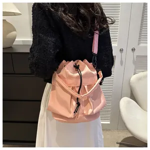Roze bucket bag met trekkoord van nylon gedragen door model in een knus interieur