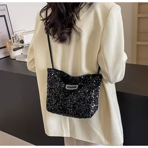 Detail of black sequined shoulder bag featuring a silver FASHION label and leather strap