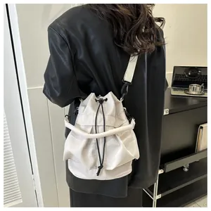 Detailopname van witte nylon bucket bag met trekkoord en brede riem op model getoond