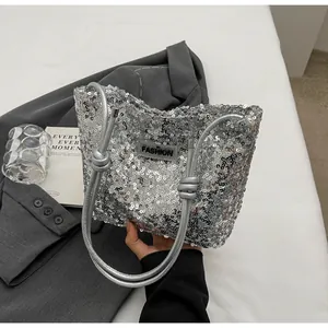 Close-up of silver sequin tote bag featuring a black fashion label and knotted handles