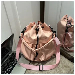 Détail du sac seau en nylon rose clair avec cordon de serrage et bandoulière assortie