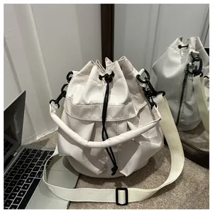Détail d'un sac seau beige minimaliste en nylon avec cordon de serrage et bandoulière large