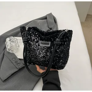 Detail of black sequin tote bag with knotted shoulder strap and fashion label on suit