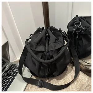 Gros plan du sac seau noir à cordon avec poignée ronde et large bandoulière