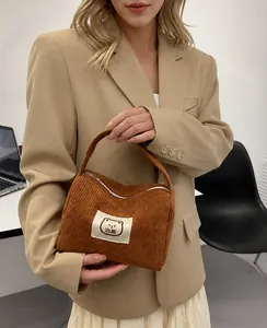 Dettaglio ravvicinato della borsa in velluto marrone con patch orsetto e cerniera