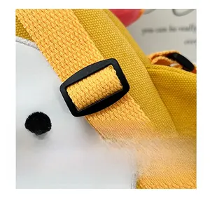 Detail of adjustable shoulder strap and embroidery on yellow canvas cartoon crossbody bag