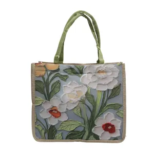 Détail du sac cabas floral avec imprimé fleuri texturé et poignée tressée verte