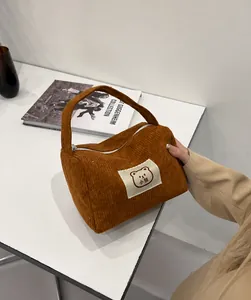 Borsa in velluto a coste marrone con etichetta di orso su una scrivania estetica