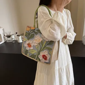 Détail du motif floral de peinture à l'huile sur un grand sac cabas aux anses vertes