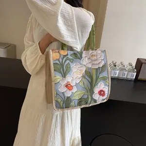 Détail d'un cabas en tapisserie florale avec bordure en jute porté par une personne